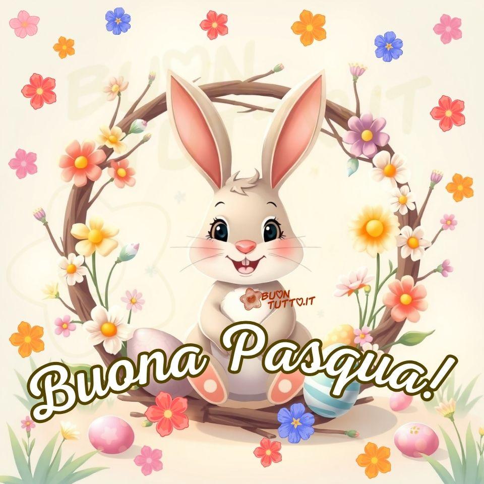 Un’illustrazione che raffigura un piccolo coniglio antropomorfo dall’aspetto adorabile, seduto in posizione frontale con un’espressione dolce e gioiosa. Ha grandi occhi neri e lucenti, guance rosate, un piccolo nasino rosa e due dentini incisivi che spuntano dal suo sorriso tenerissimo. Il pelo, morbidissimo, è di un caldo marrone chiaro/beige, mentre il petto e la pancia sono di un bianco candido. Il coniglietto è incorniciato da una ghirlanda circolare composta da rami intrecciati color marrone scuro, decorata con numerosi fiori di campo dai toni gialli, rosa, bianchi e viola, insieme a piccoli boccioli verdi. Lo sfondo è un beige chiarissimo e neutro, impreziosito da una miriade di fiorellini pastello (rosa cipria, giallo crema e lilla). Accanto al coniglio, sul prato, sono presenti uova di Pasqua color pastello. È un’immagine perfetta per augurare Buona Pasqua, perché trasmette pace, calore, amicizia, affetto, gioia, serenità e una grande tenerezza. Nella parte inferiore dell’illustrazione compare la scritta “Buona Pasqua!” in forma semicircolare, realizzata con un elegante carattere corsivo bianco con contorno dorato. Questa immagine fa parte di una nuova raccolta di splendide rappresentazioni dedicate agli auguri di Buona Pasqua, create per essere scaricate gratuitamente e condivise con amici, persone care, familiari, parenti e gruppi su WhatsApp, Facebook, Instagram, Pinterest, Telegram, X (Twitter), LinkedIn e tutte le tue piattaforme social preferite. Autore BuonTutto.it 
