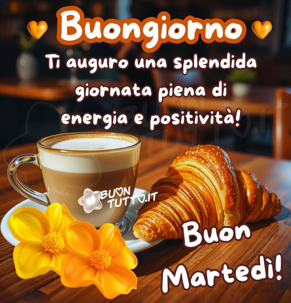 immagini-di-buon-martedi-buongiorno-splendida-giornata-frase-positiva-energia-cappuccino-cornetto-fiori-bellissima-scaricare-gratis-buontutto Il primo piano mostra una tazza di vetro trasparente contenente un cappuccino, posata su un piattino bianco, accanto alla tazza c'è un croissant, poggiati su un tavolo di legno scuro, con una trama visibile. Sul piattino sono poggiati anche due dalie di colore giallo e arancione chiaro. Lo sfondo è un locale sfocato, presumibilmente un caffè o una pasticceria, dove si possono distinguere sedie e tavoli, con una luce soffusa che crea un'atmosfera calda e accogliente. Nella parte alta dell'immagine c'è scritto in un carattere corsivo grassetto grande di colore bianco e contorno marroncino-arancione buongiorno con ai lati due cuori marroni sfumati. Di sotto dello stesso carattere e di colore bianco con contorno marrone Ti auguro una splendida giornata piena di energia e positività! Nella parte bassa a destra dello stesso colore e carattere Buon martedì! Un'immagine che trasmette accoglienza, serenità, positività, energia e tanto buonumore da scaricare gratis e condividere con amici, cari, familiari, parenti gruppi tramite WhatsApp, Facebook, X Twitter, Pinterest, Telegram, LinkedIn, Instagram e le tue piattaforme social preferite. Autore BuonTutto.it