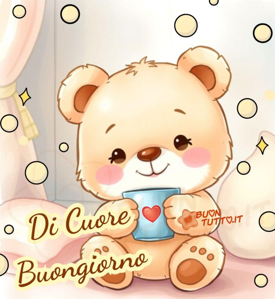 Un'illustrazione che ritrae un adorabile orsetto di peluche, con il pelo color miele e guanciotte rosa. Ha occhi grandi e scintillanti che irradiano pura dolcezza. L'orsetto tiene tra le sue piccole zampe un'incantevole tazza azzurra decorata con un cuore rosso. È seduto in un ambiente accogliente, circondato da cuscini morbidi e bolle di luce che fluttuano dolcemente, creando un'atmosfera serena e sognante. Nella parte bassa a sinistra dell'immagine c'è scritto in posizione trasversale in un carattere corsivo elegante di colore marrone e contorno evidenziato di giallo Di Cuore Buongiorno. Un'immagine bellissima che esprime un senso di calore, conforto e affetto da scaricare gratis e condividere con amici, cari, familiari, parenti gruppi tramite WhatsApp, Facebook, X Twitter, Pinterest, Telegram, LinkedIn, Instagram e le tue piattaforme social preferite. Autore BuonTutto.it 